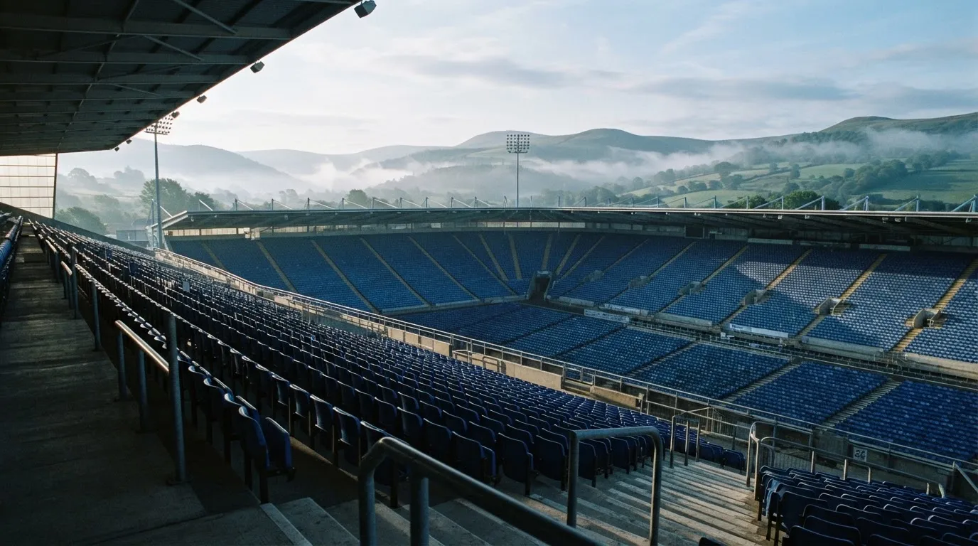 Ein leeres Stadion im Morgenlicht mit Blick auf die Sitzreihen, im Hintergrund Hügel und aufsteigender Nebel.