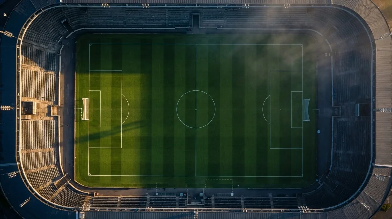 Ein Fussballplatz von oben gesehen, die Linien bilden ein helles Muster auf dem Rasen, Drohnenperspektive in der Morgendämmerung.